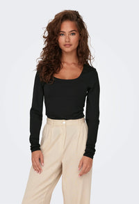 Woman wearing a black long-sleeve top and beige pants on a white background