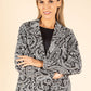 Woman wearing a black and white patterned blazer on a beige background