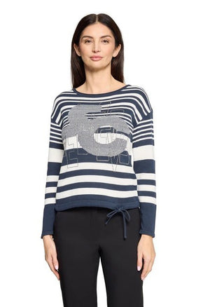 Woman wearing a blue and white striped sweater with a graphic design on a white background