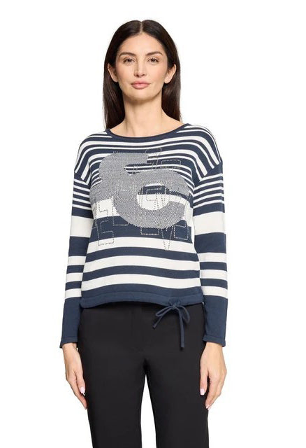 Woman wearing a blue and white striped sweater with a graphic design on a white background