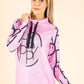 Woman wearing a pink hoodie with black graphics on a beige background