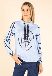 Woman wearing a light blue hoodie with black geometric patterns and text on a beige background