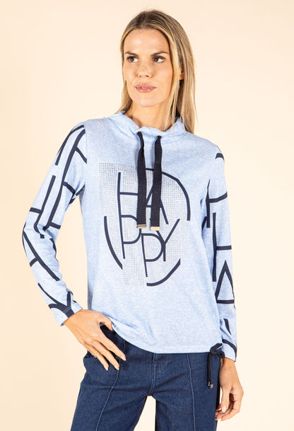 Woman wearing a light blue hoodie with black geometric patterns and text on a beige background