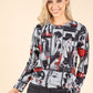 Model in grey and red Paris pattern top on beige background