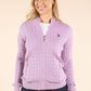 Woman wearing a purple cable knit cardigan on a beige background