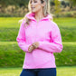Woman wearing a pink sweater standing in a grassy outdoor area