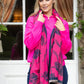 Woman wearing a bright pink scarf with a floral pattern outdoors.