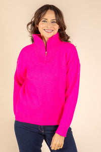Woman wearing a bright pink sweater against a beige background
