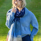 Woman wearing a blue sweater and scarf outdoors on grass