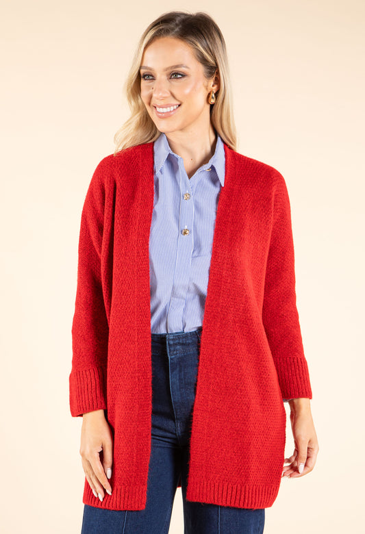 Woman wearing a gray cardigan over a white turtleneck on a beige background