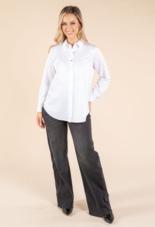 Woman wearing a white shirt and dark jeans on a beige background