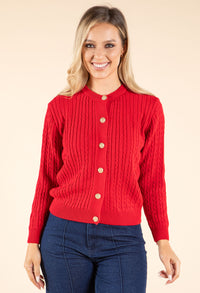 Woman wearing a red cardigan with gold buttons on a beige background