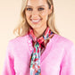 Woman wearing a pink sweater and colorful scarf against a beige background