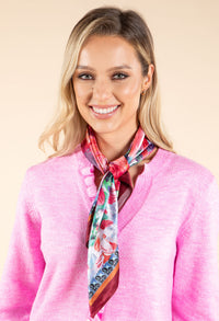 Woman wearing a pink sweater and colorful scarf against a beige background