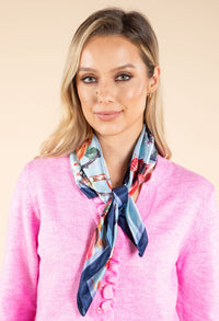 Woman wearing a colorful scarf around her neck against a beige background