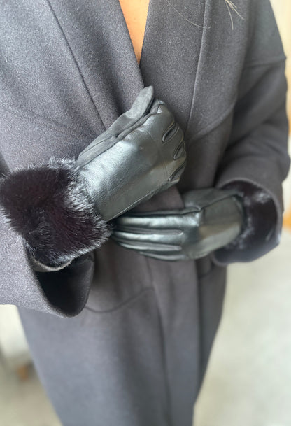 Gray coat with black leather gloves and fur cuffs on a blurred background