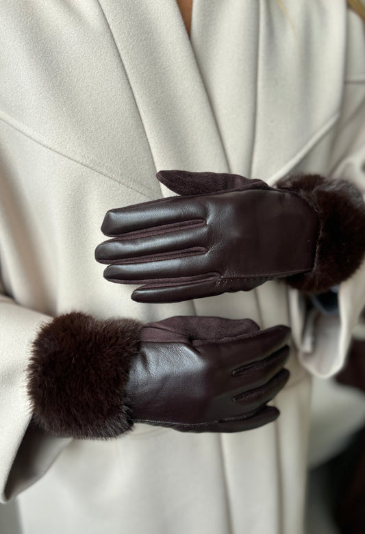 Gray coat with black leather gloves and fur cuffs on a blurred background