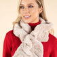 Woman wearing a red sweater and beige fluffy scarf against a beige background