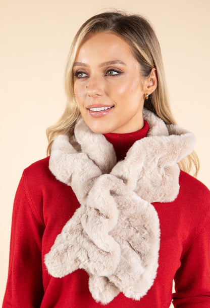 Woman wearing a red sweater and beige fluffy scarf against a beige background