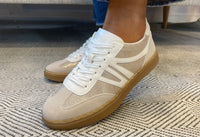 Beige sneakers with white laces on a patterned carpet