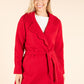 Woman wearing a red coat on a beige background