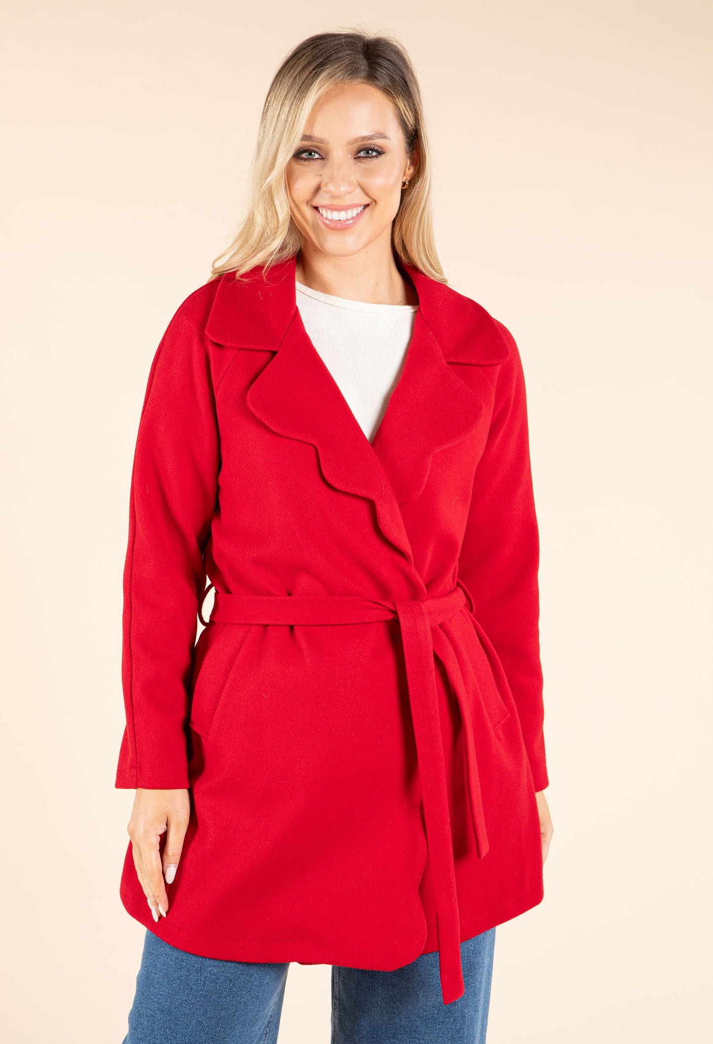 Woman wearing a red coat on a beige background