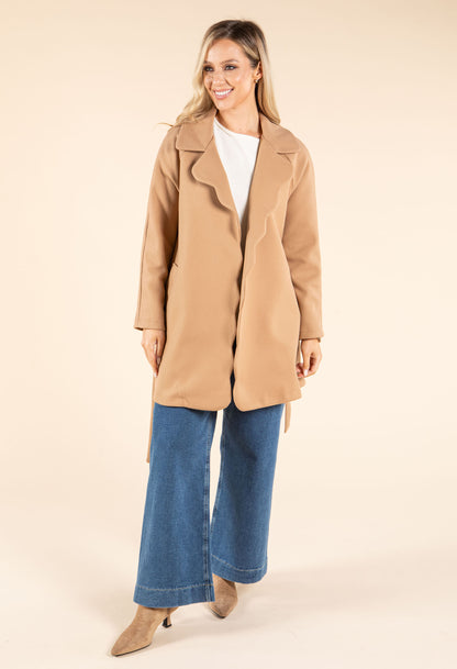 Woman wearing a beige coat and blue jeans on a beige background