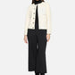 Woman wearing a cream jacket over a black top and pants on a white background
