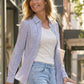 Woman walking outdoors holding a coffee cup, wearing a striped shirt and jeans.