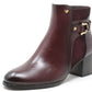 Burgundy ankle boot with gold buckle on a white background