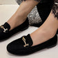 faux suede loafer with gold buckle on a models foot on a white background
