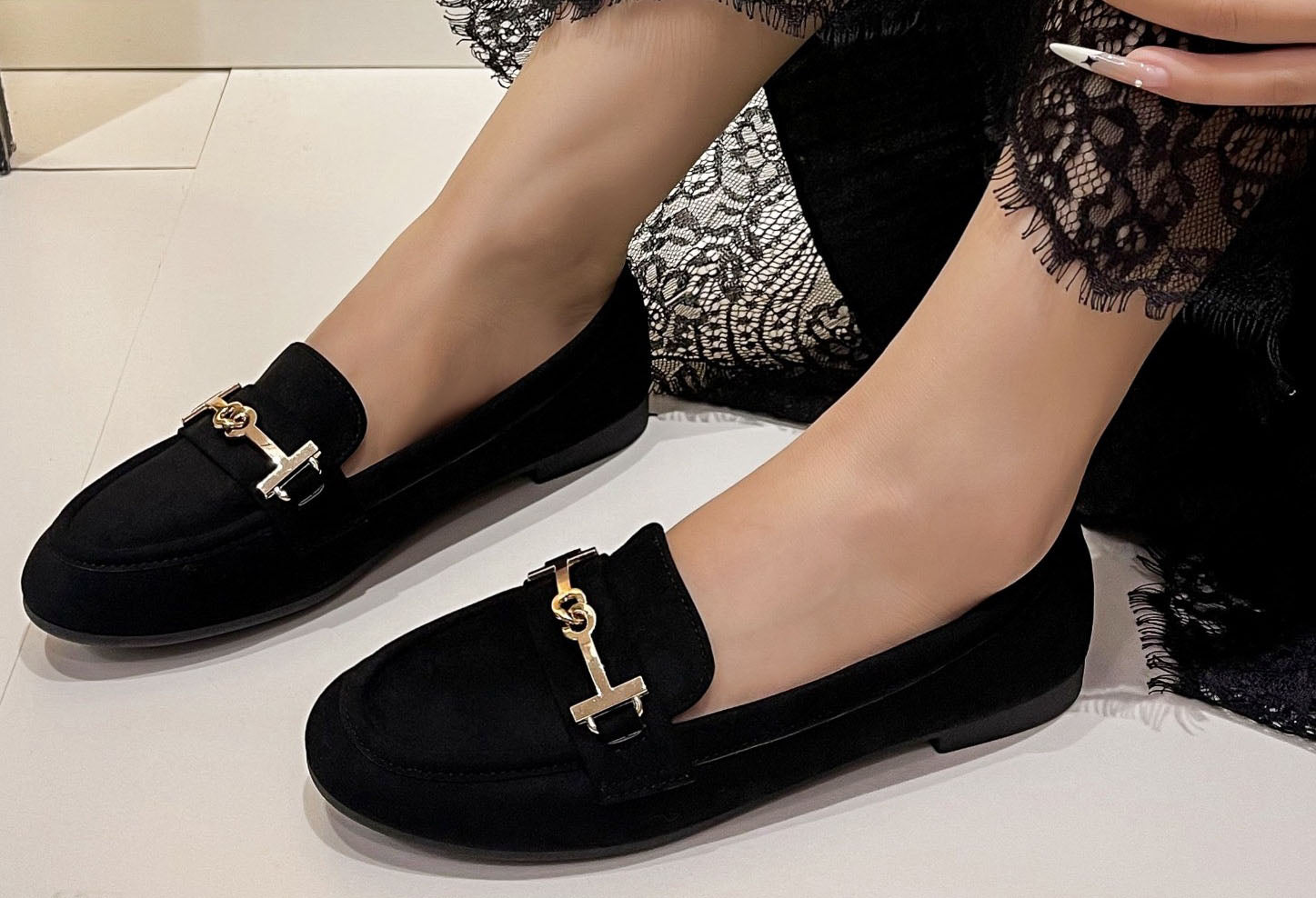 faux suede loafer with gold buckle on a models foot on a white background