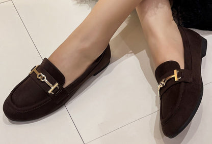 faux suede loafer in brown on a models foot. With a gold buckle detail.