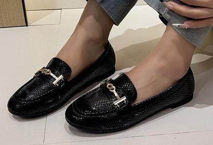 faux snake effect loafer with gold buckle on a models foot with a white background