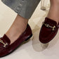 faux snake effect loafer with gold buckle on a models foot with a white background