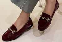 faux snake effect loafer with gold buckle on a models foot with a white background
