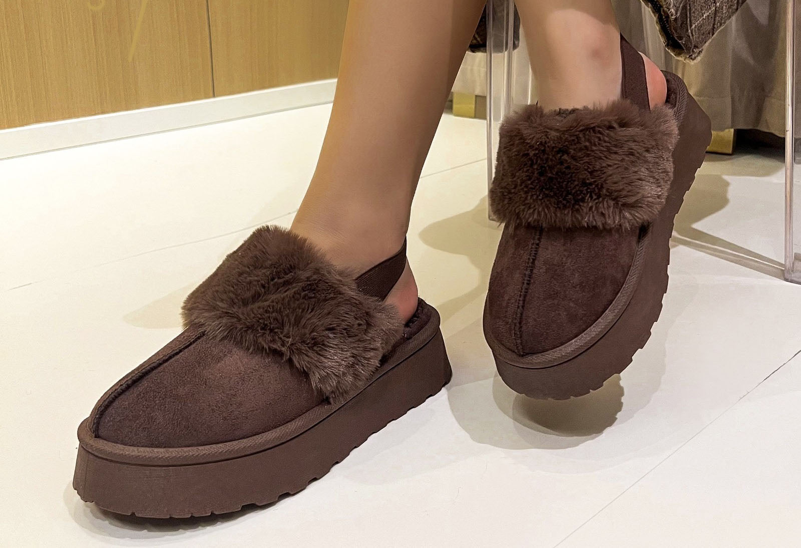 faux fur slip on boot with ankle strap and faux fur cuff. On a models foot with a white background