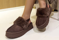 faux fur slip on boot with ankle strap and faux fur cuff. On a models foot with a white background