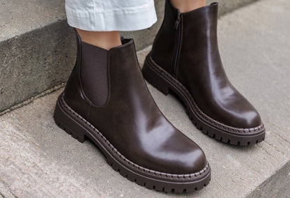 Brown leather boots worn by a person on a concrete surface