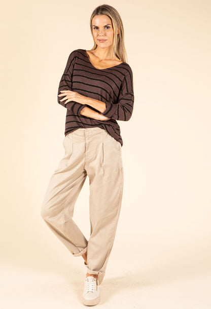 Woman wearing a striped sweater and beige pants on a beige background