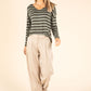 Woman wearing a striped sweater and beige pants on a beige background