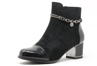Black ankle boot with chain detail on a white background