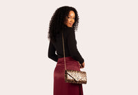 Woman holding a leopard print handbag against a plain background