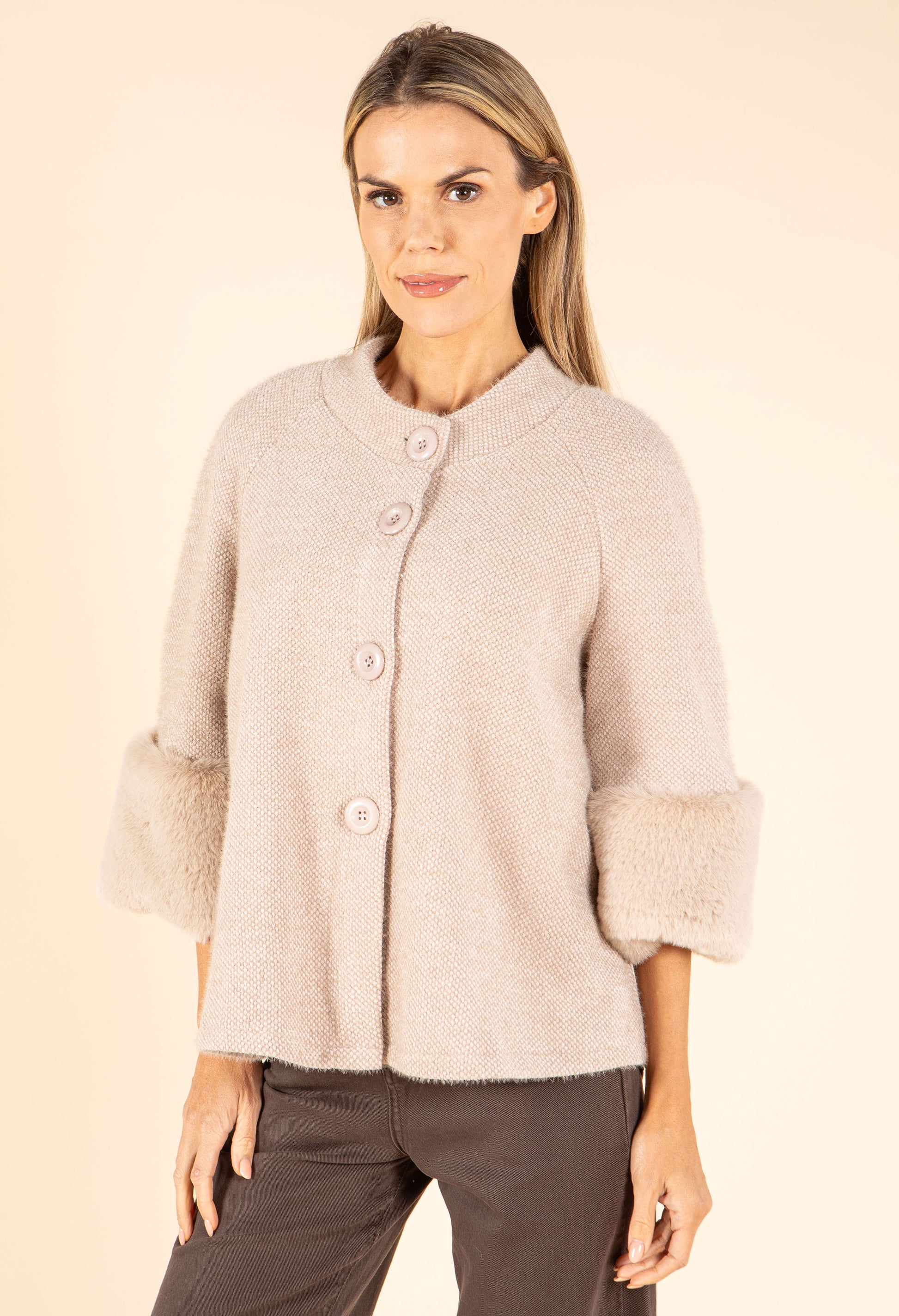 Woman wearing a light pink textured jacket on a beige background