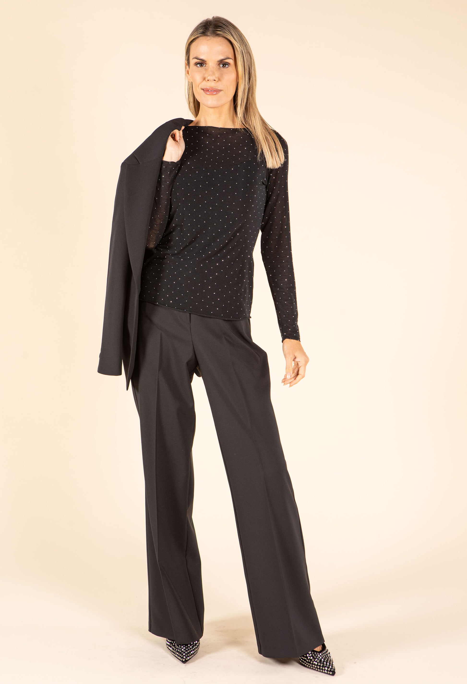 Woman wearing a black outfit with a pattern on a beige background