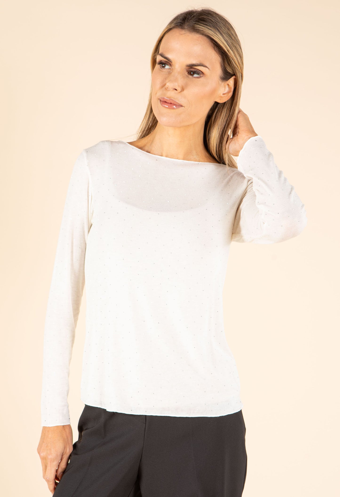 Woman wearing a white long-sleeve top against a beige background