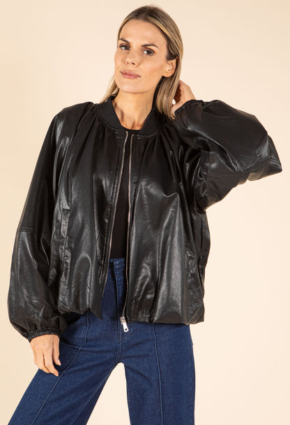 Woman wearing a black leather jacket and blue jeans on a beige background