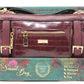 Maroon handbag with gold accents on a decorative box