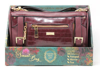 Maroon handbag with gold accents on a decorative box