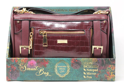 Maroon handbag with gold accents on a decorative box